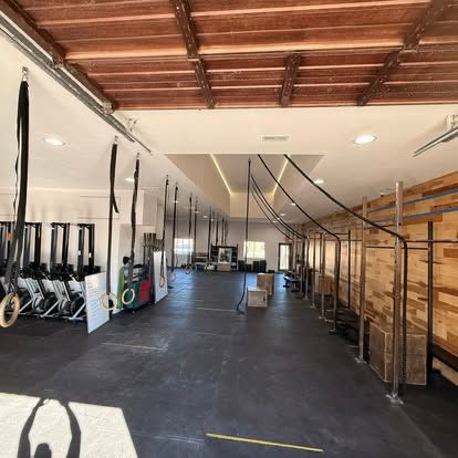 Finished functional-fitness gym with rig stations, rowers, and wood feature walls